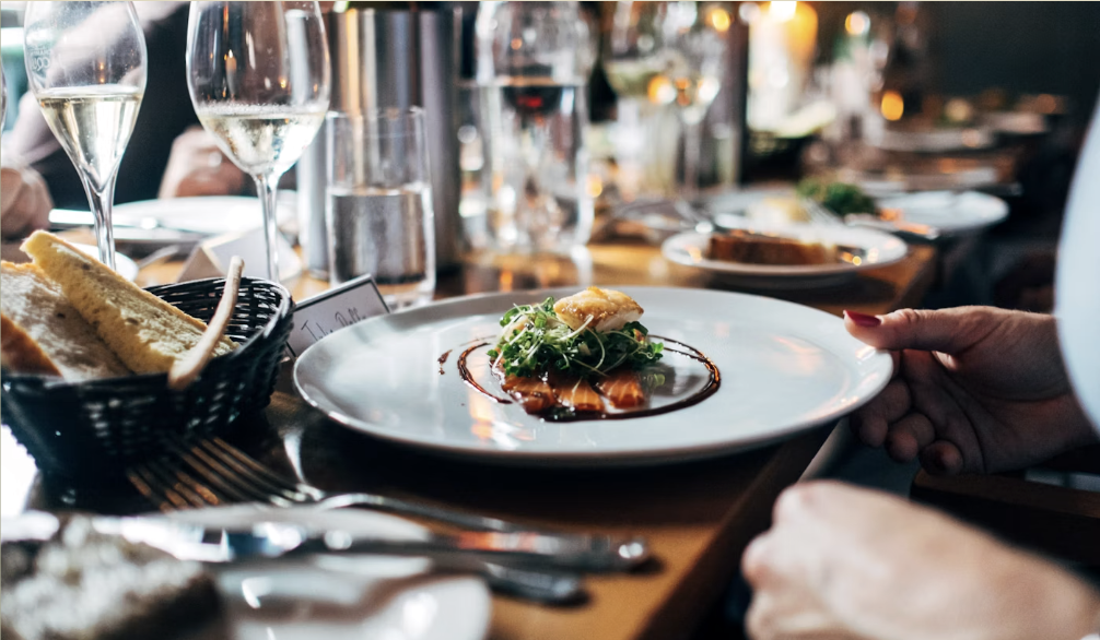 Table dressée en soirée, verres à vin et assiette servie à la table d'Ombra